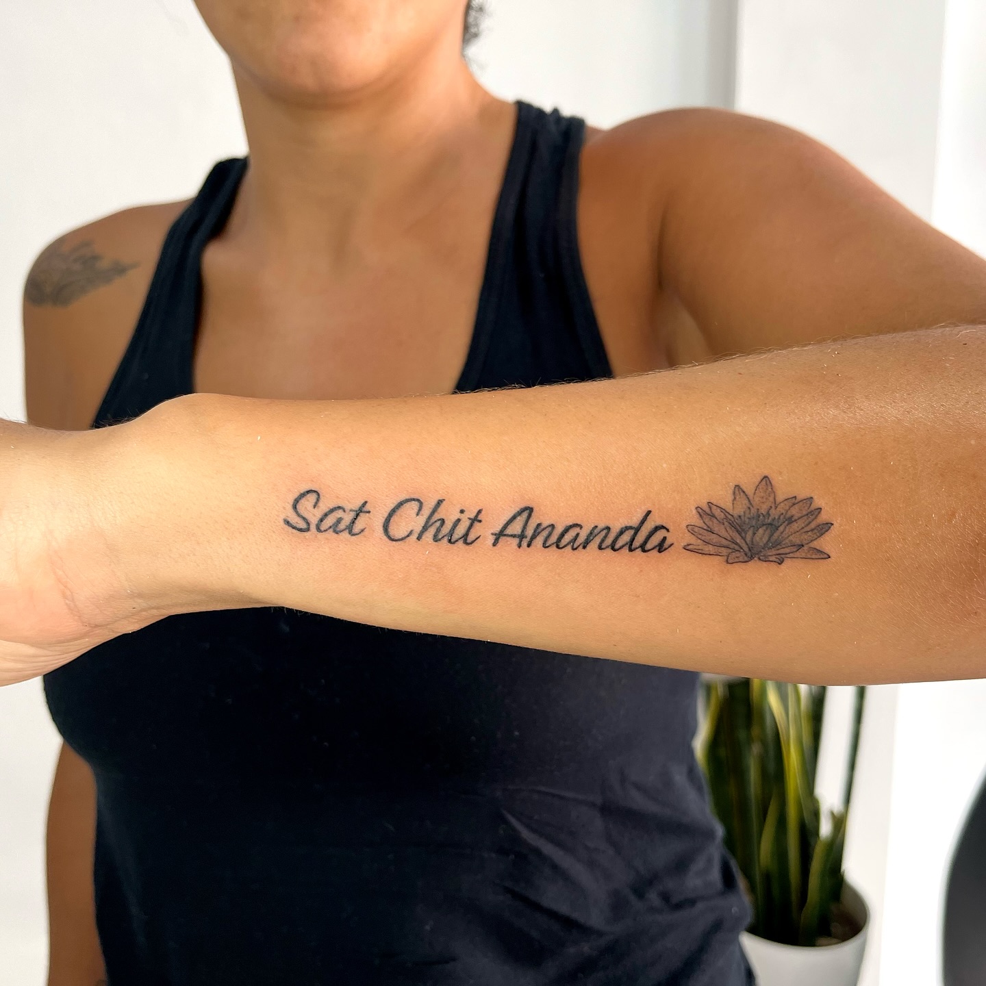 Flor y mantra en brazo